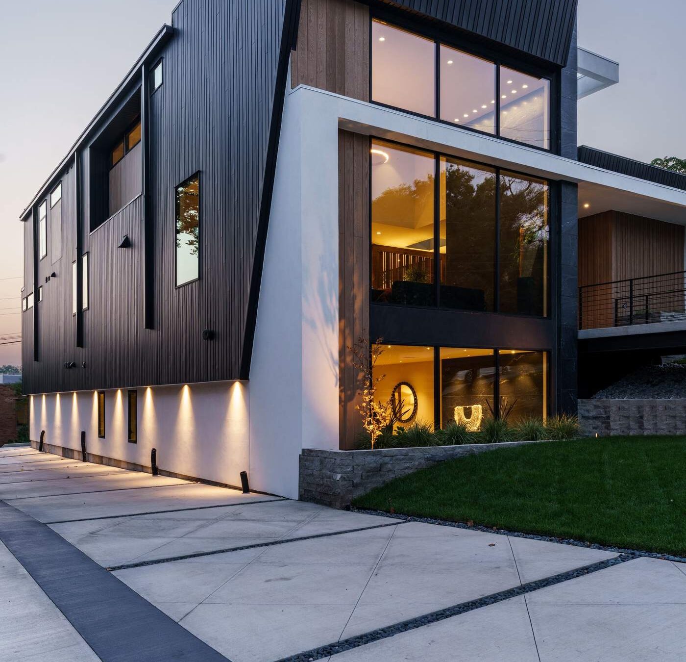 Angular contemporary custom home exterior illuminated at dusk, Hickok Homes new construction