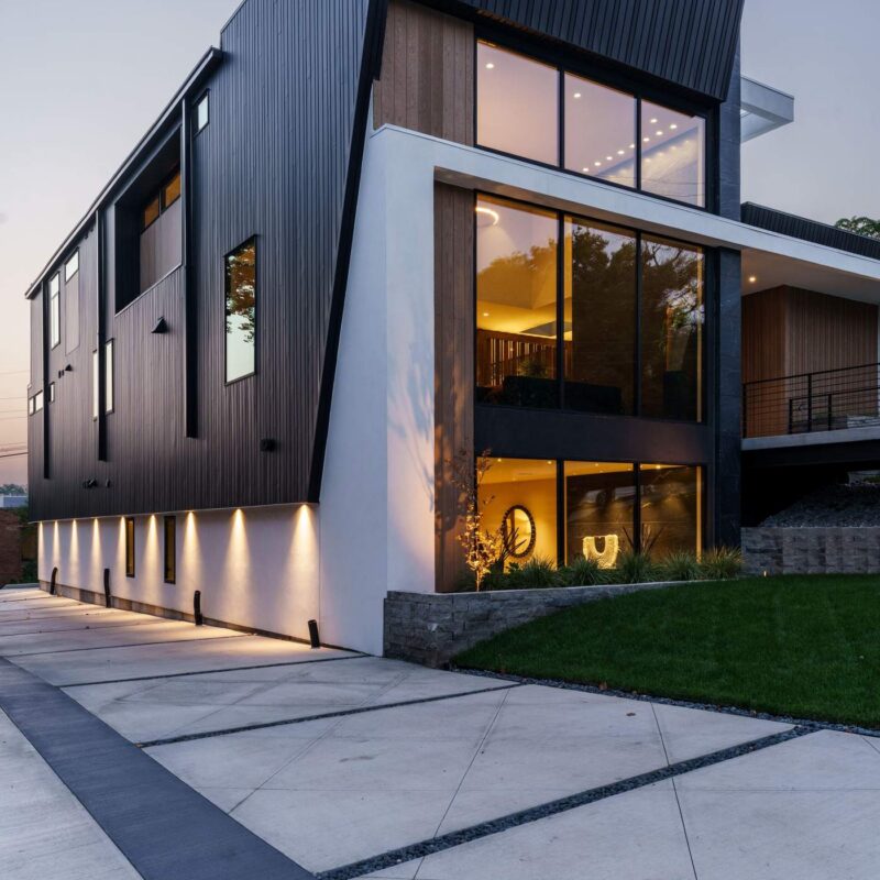 Angular contemporary custom home exterior illuminated at dusk, Hickok Homes new construction