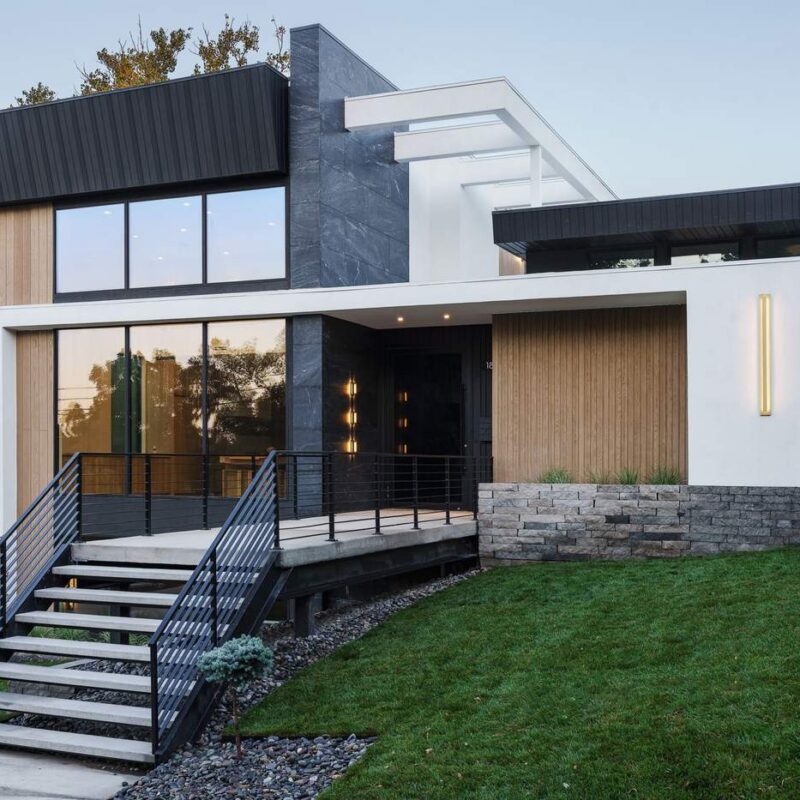 Contemporary custom home exterior with black metal cladding and warm wood accents, built by Hickok Homes