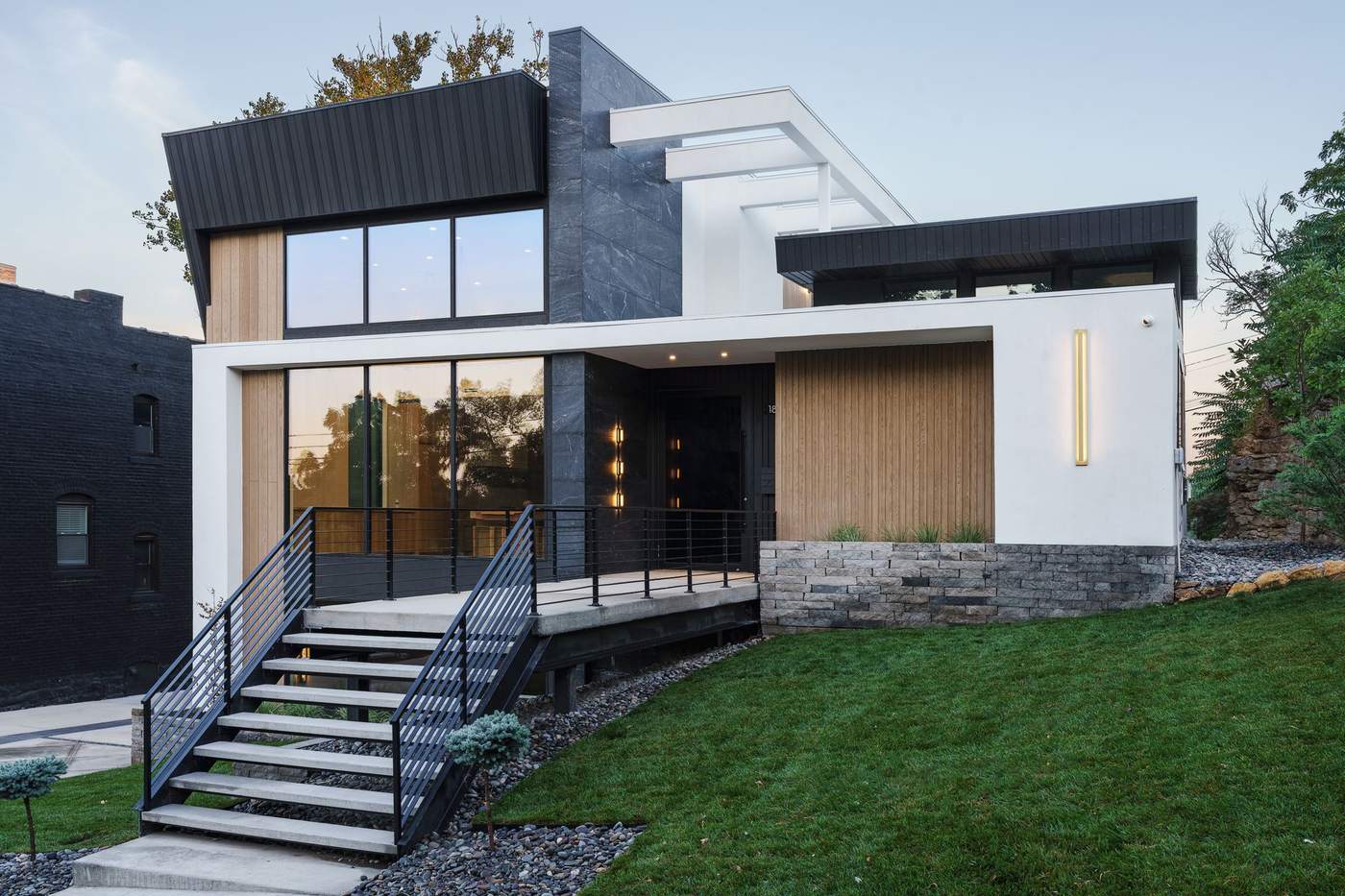 Contemporary custom home exterior with black metal cladding and warm wood accents, built by Hickok Homes