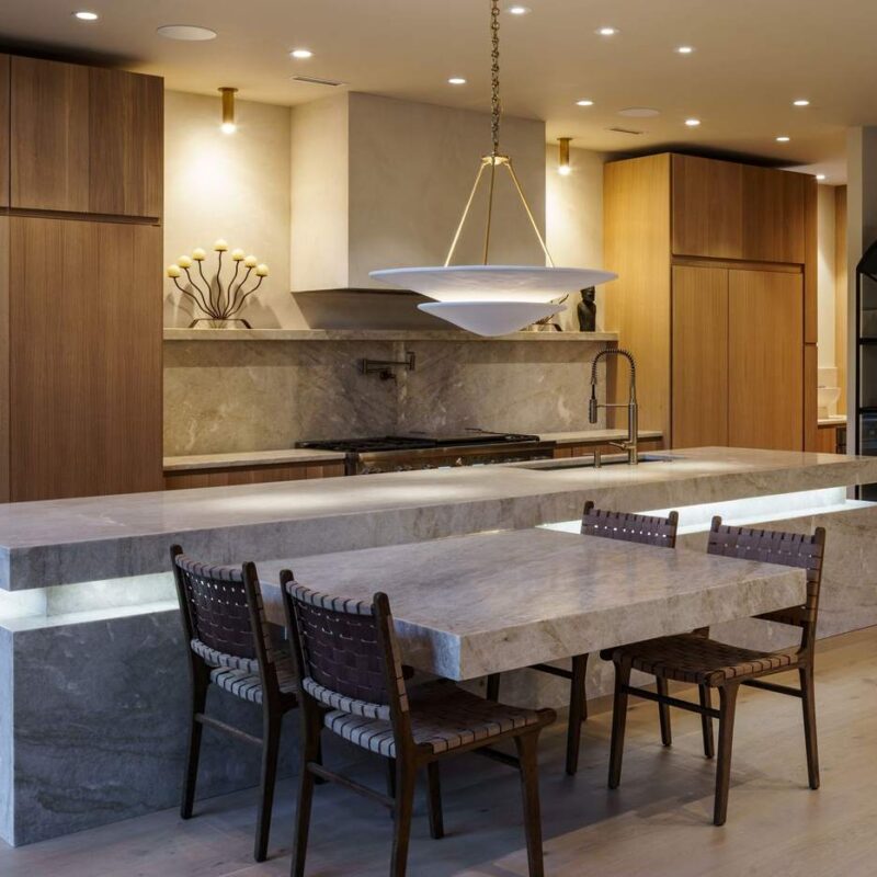 Custom kitchen with waterfall stone island and walnut cabinetry, built by Hickok Homes