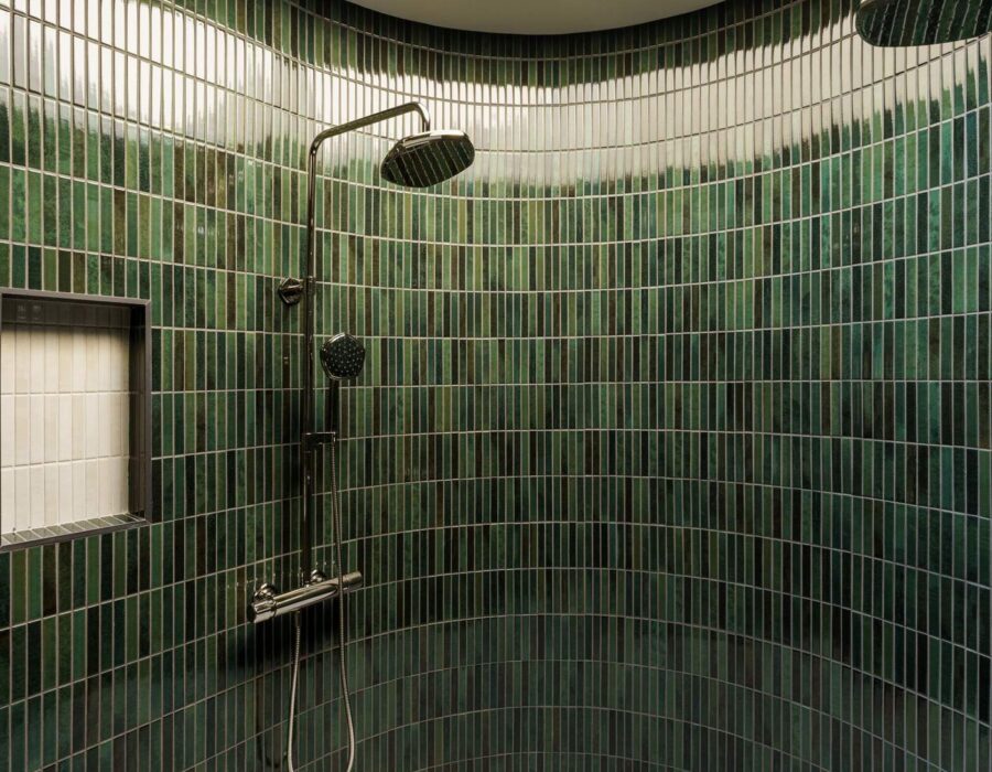Curved emerald tile walk-in shower in a custom primary suite
