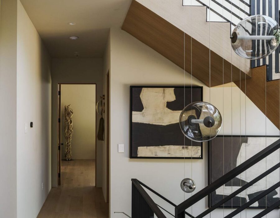 Modern staircase and hallway with black metal railing and wide plank flooring