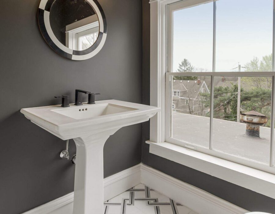 Renovated bathroom with pedestal sink and geometric tile flooring