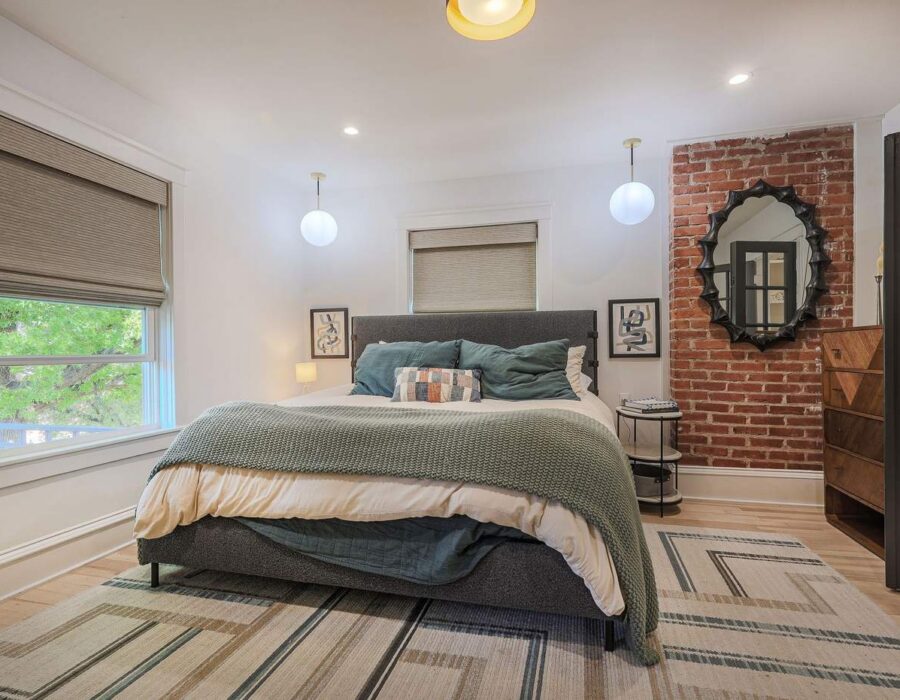 Primary bedroom with exposed brick accent wall after a full home remodel