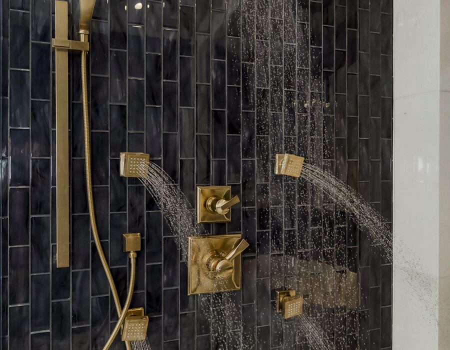 Custom black tile walk-in shower with brushed gold fixtures