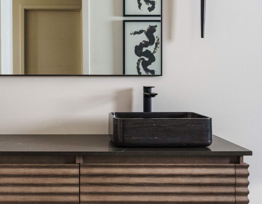 Bathroom vanity with matte black vessel sink and wood paneling