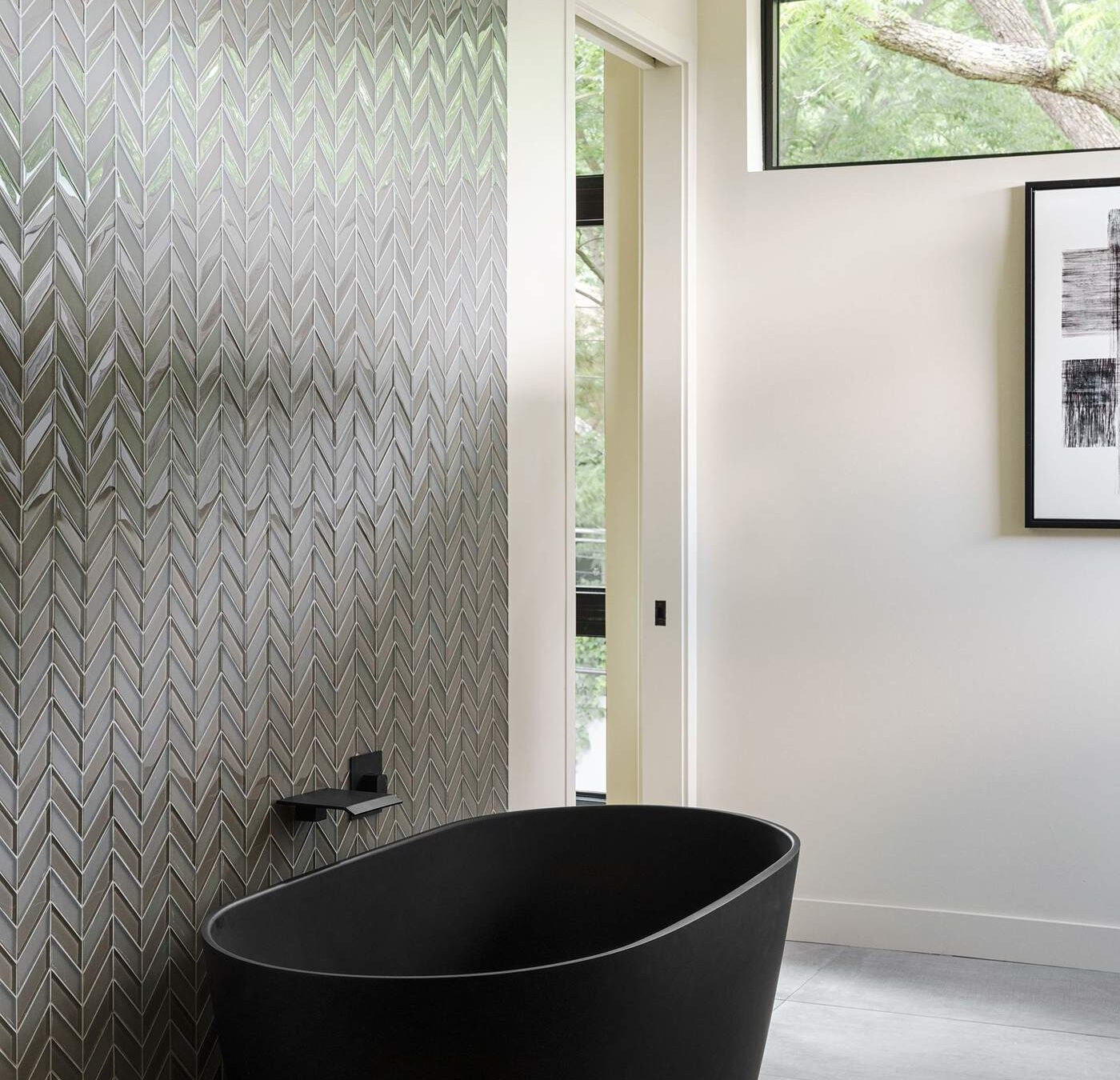 Freestanding black soaking tub with textured tile wall