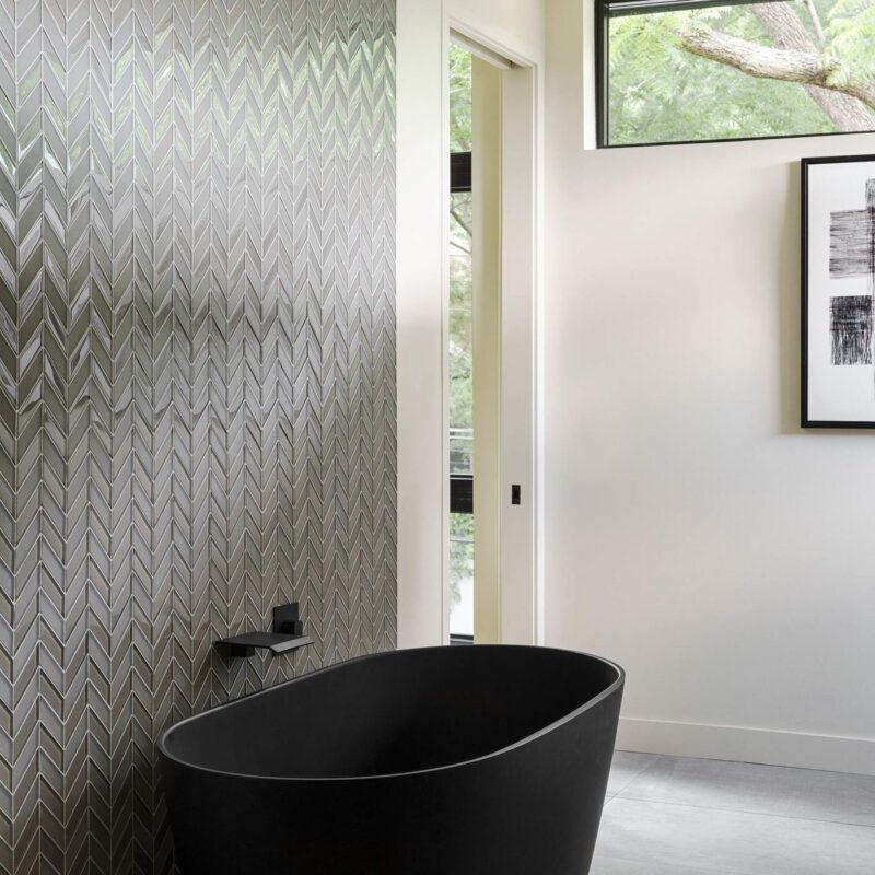 Freestanding black soaking tub with textured tile wall