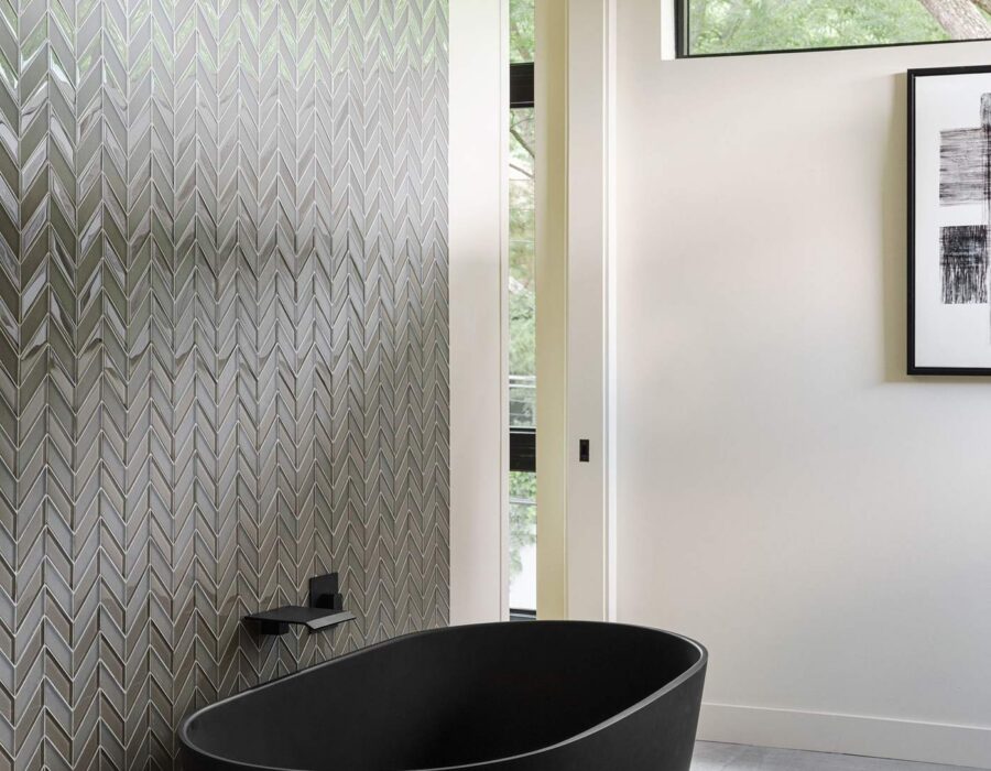 Freestanding black soaking tub with textured tile wall