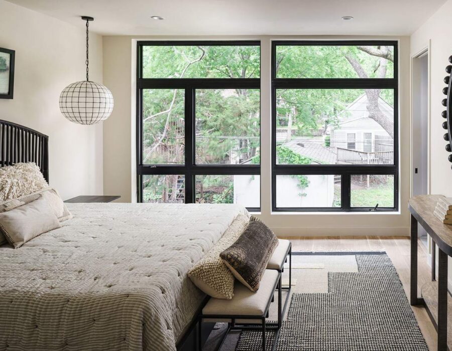 Primary bedroom with wall of windows overlooking mature trees